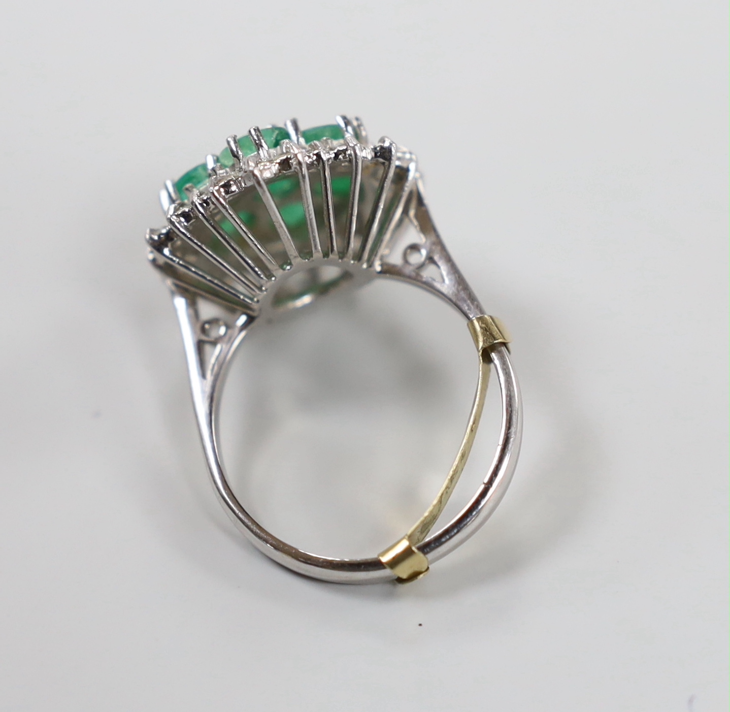 A modern 18ct white gold, emerald and diamond cluster set dress ring, size P/Q, gross weight 7.8 grams.